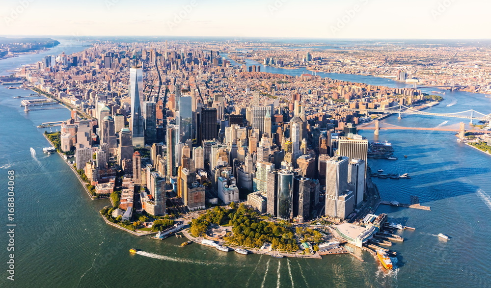 Widok lotniczy na Dolny Manhattan w Nowym Jorku z charakterystycznymi wieżowcami, w tym One World Trade Center. W tle rzeki Hudson i East River oraz mosty Brooklyn Bridge i Manhattan Bridge. 