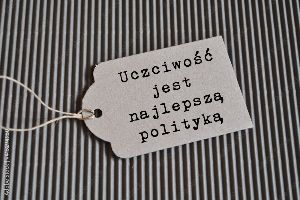 Biała etykieta z napisem 'Uczciwość jest najlepszą polityką' na czarno-białym prążkowanym tle, symbolizująca wartości w biznesie